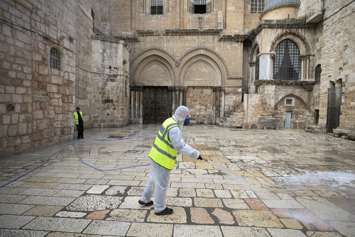 עובד מחטא את החצר הקדמית של כנסיית הקבר הסגורה בירושלים, ב-30 במרץ 2020 (צילום: אוליבייה פיטוסי / פלאש90)