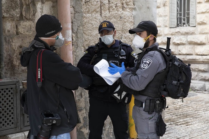 שוטרים נותנים דו"ח בסך 5,000 שקל לצלם במהלך טקס יום שישי הטוב בעיר העתיקה בירושלים, ב-10 באפריל 2020 (צילום: אורן זיו)