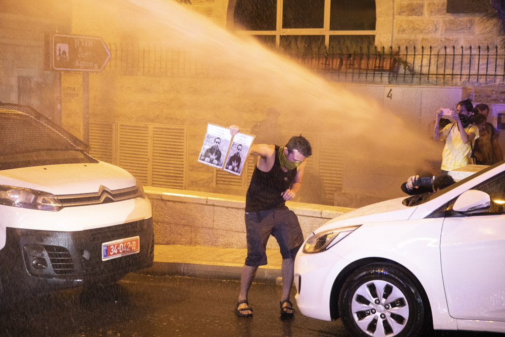 במהלך מפגין מחזיק צילום של איאד אל חאלק מול מכתזית משטרתית, מחאה בכיכר פריז מול מעון ראש הממשלה, 22 ביולי 2020 (צילום: אורן זיו)