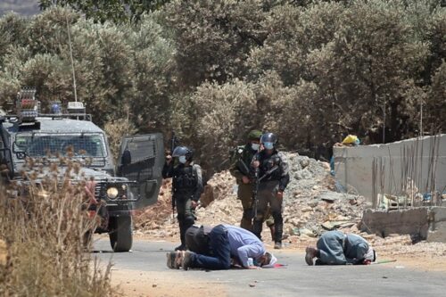 פלסטינים מתפללים בקרבת חיילים ישראליים ליד הכפר תורמוס עייא בגדה המערבית, במהלך מחאה נגד הקמת התנחלויות, ב-7 באוגוסט 2020 (צילום: פלאש90)