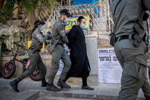 שוטרים עוצרים חרדי בפשיטה על בית כנסת בשכונת גאולה בירושלים שנפתח בניגוד לתקנות הקורונה, ב-14 באוקטובר 2020 (צילום: יונתן זינדל / פלאש90)