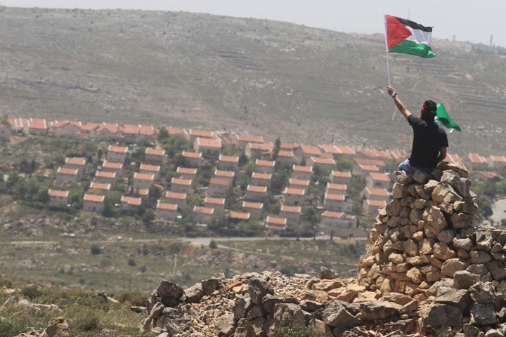 מירון בנבנישתי כתב שהסיפוח הוא בלתי הפיך. הוא צדק. מפגין פלסטיני על רקע התנחלות עפרה בגדה המערבית (צילום: עיסאם רימאווי / פלאש 90)
