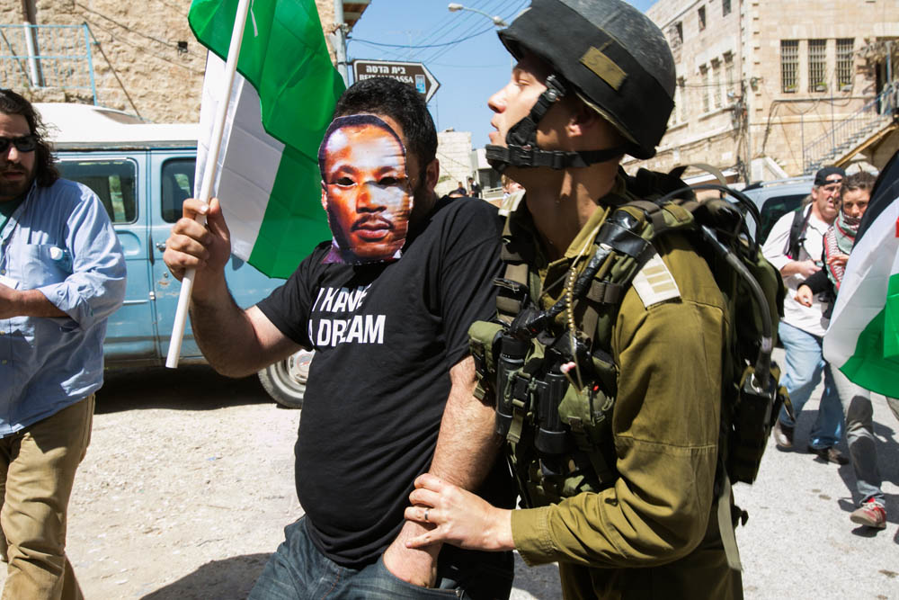 חיילים עוצרים את עיסא אמרו, עם מסכה של מרתין לותר קינג, ברחוב השוהדא בחברון בזמן ביקור אובמה בישראל, מרץ 2013 (צילום: אקטיבסטילס)