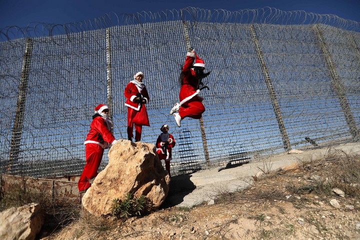 פלסטינים לבושים כסנטה קלאוס מפגינים ליד חומת ההפרדה באזור בית לחם, ב-23 בדצמבר 2019 (צילום: וויסאם השלמון / פלאש90)
