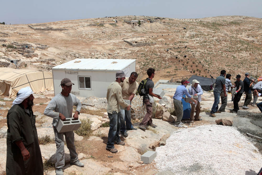 פלסטינים ופעילים עוזרים לבנות בית באום פראג׳ בשטח סי בדרום הר חברון, 2012 (צילום: אקטיבסטילס)