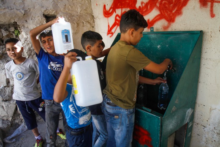 פלסטינים ממלאים מים בבקבוקים בכפר בלטה ליד שכם, ב-2018 (צילום: נאסר אישתיה / פלאש90)