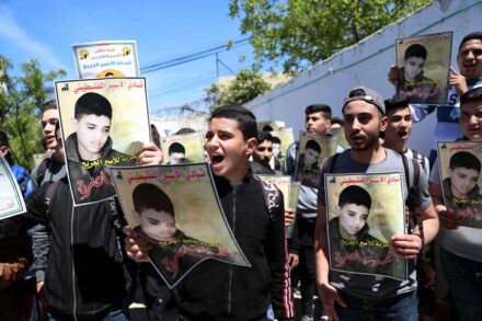 פלסטינים מחזיקים תמונות של אחמד מנאסרה, בהפגנה למען שחרורו בחברון, ב-13 באפריל 2022 (צילום: ויסאם השלמון / פלאש90)