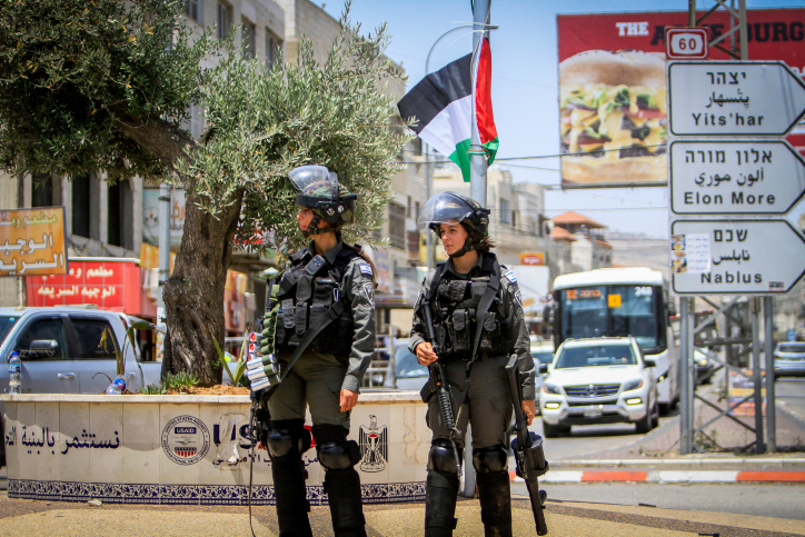 לפני תחילת המאבק, בקושי היו דגלים פלסטינים בחווארה. חיילים על רקע דגל פלסטיני במרכז העיירה (צילום: נאסר שתאיה / פלאש 90)