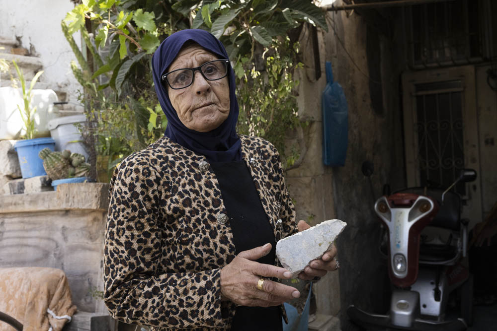 פאטמה סאלם מחזיקה אבן שנזרקה לאבן ביתה, לאחר מתקפת מתנחלים בשייח׳ ג׳ראח, 14 ברוקטוסר 2022 (צילום: אורן זיו)