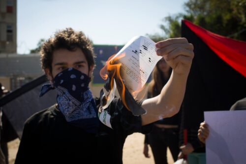 צעיר שורף צו גיוס בהפגנת הזדהות עם סרבניות שנכלאו, ליד הבקו"ם בתל השומר, ב-31 בינואר 2016 (צילום: אורן זיו)