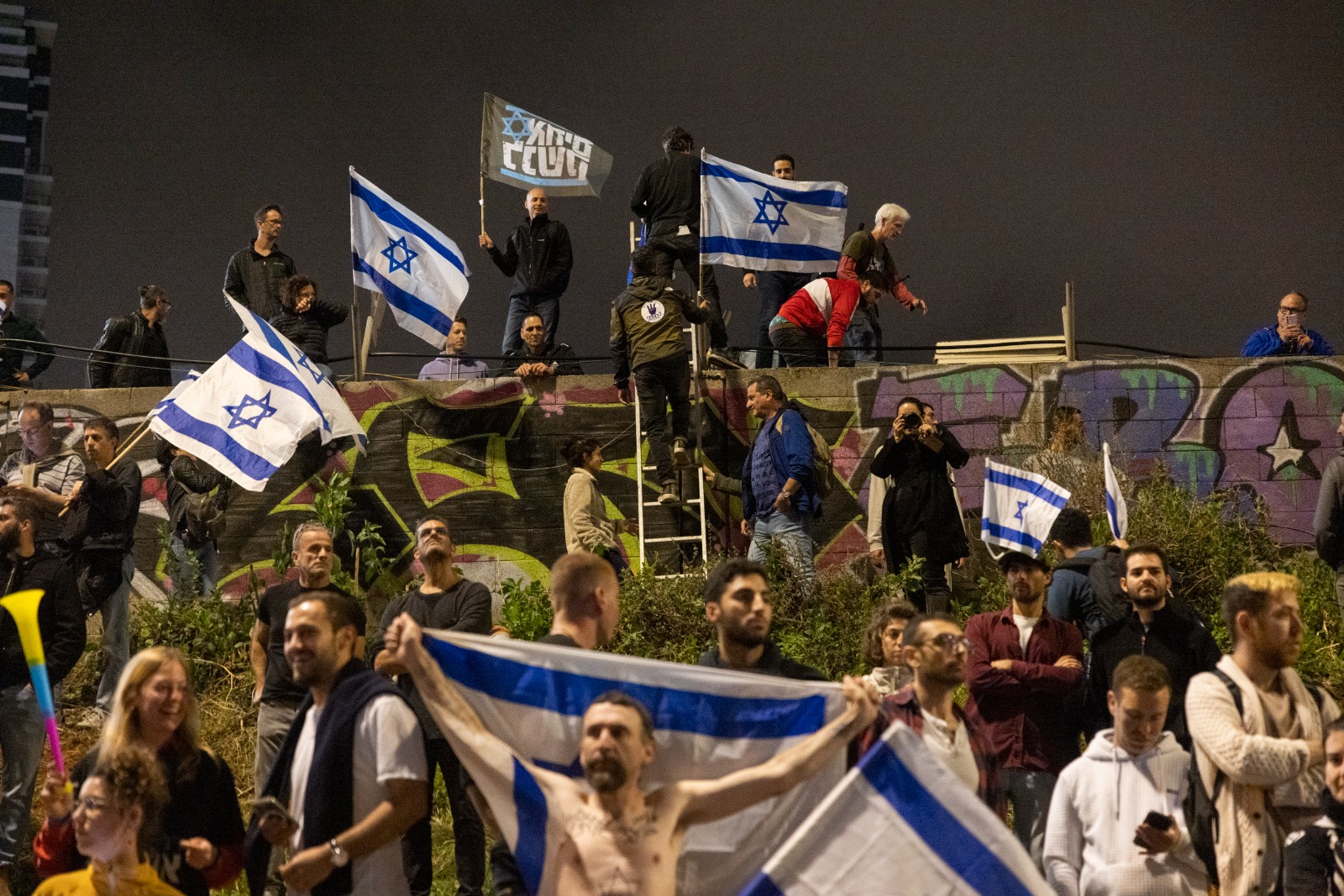 מפגינים עזרו אחד לשני לרדת אל הכביש. חסימת האיילון, 25.3.2023 (צילום: אורן זיו)
