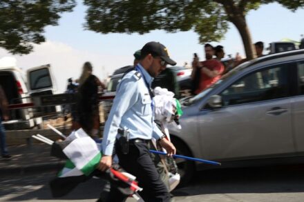המשטרה טענה בבג"ץ שהחרמת דגלים היא "אירוע חריג". המציאות שונה. שוטר עם דגלים פלסטינים שהחרים עם פתיחת השגרירות האמריקאית בירושלים ב-2018 (צילום: אורן זיו)