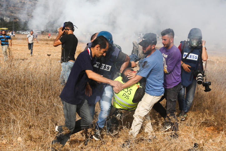 הזיהוי הברור כעיתונאים לא מנע ירי של הצבא. פלסטינים נושאים עיתונאי שנפצע מירי הצבא ליד שכם, אוקטובר 2018 (צילום: פלאש 90) 