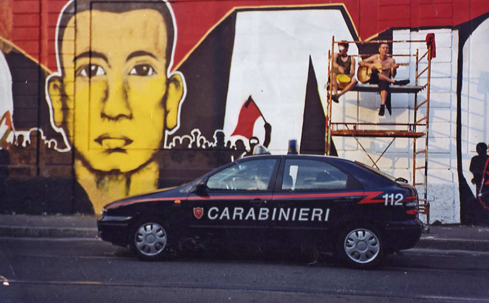 עם ציור קיר של קרלו ג'וליאי, הצעיר שנהרג על ידי המשטרה בגנואה, 2009 (CC BY-NC-ND 2.0 bbbelo)
