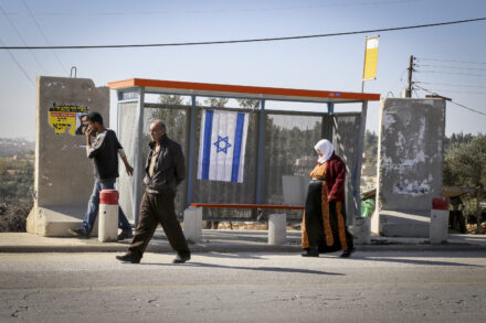 ימי הטרור הישראלי כימי ההתיישבות היהודית בארץ, שתמיד התקדם נגד רצון האוכלוסיה המקומית. פלסטינים חולפים על פני תחנת אוטובוס בכניסה להתנחלות אלון שבות, 11 בנובמבר 2014 (צילום: גרשון אלינסון / פלאש 90)