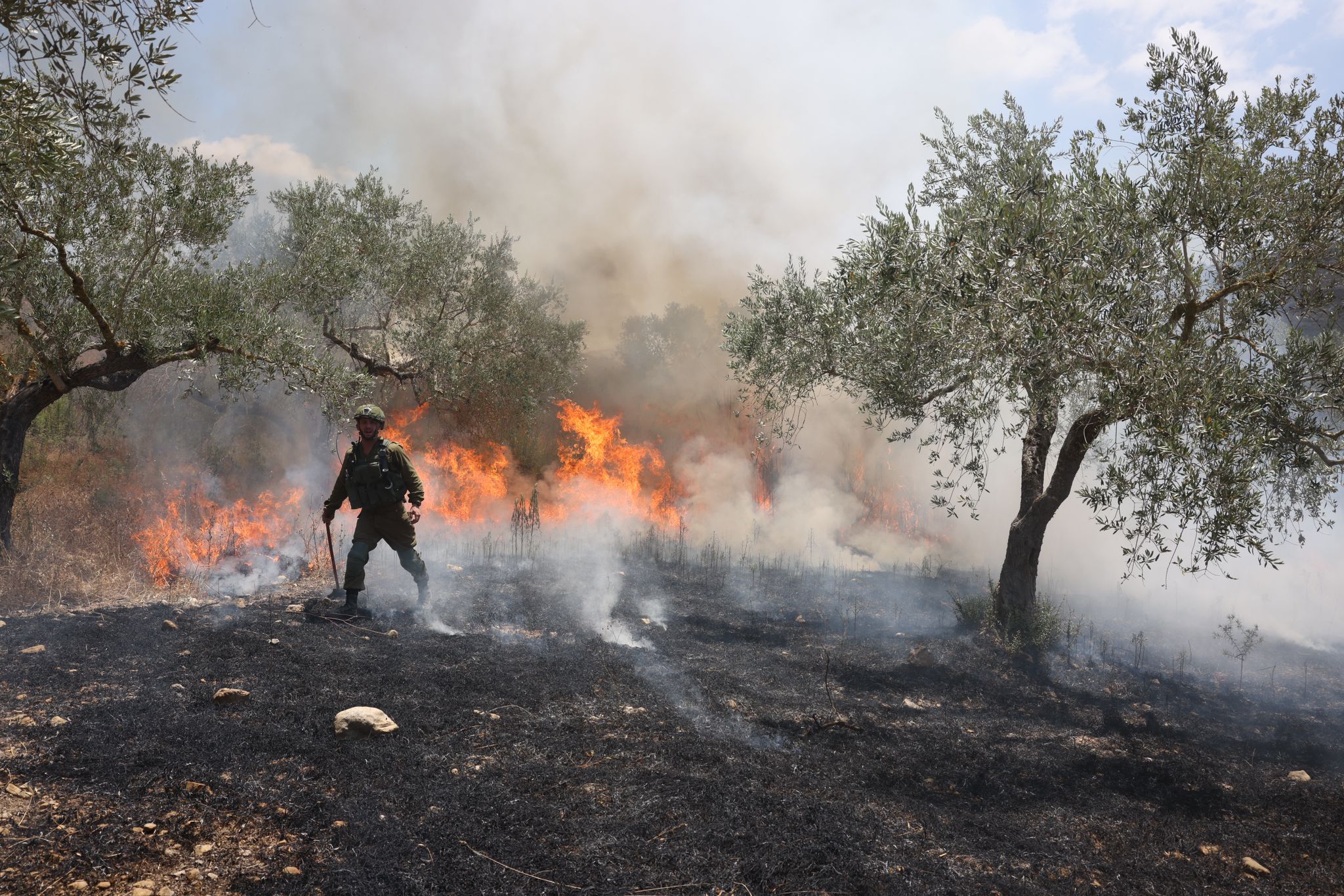 חייל מנסה לכבות שריפה שהחלה בעבקות ירי גז מדמיע במהלך צעדת מחאה לחומש, 7 ביולי 2023 (צילום: אורן זיו)