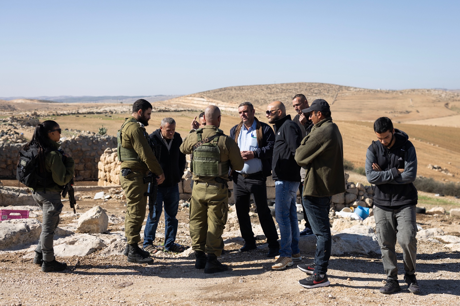 ראש הכפר ח'ירבת זנותה, פאיז אל-תל (במרכז בחולצה כחולה) ותושבים, מדברים עם אנשי המנהל האזרחי, ליד שרידי הכפר, ב-29 בנובמבר 2023 (צילום: אורן זיו)