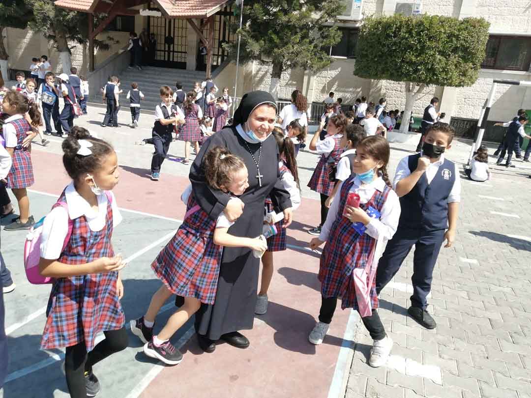 האחות נבילה סאלח, מנהלת בית הספר של האחיות רוזרי בעיר עזה, עם תלמידים (צילום: באדיבות Aid to the Church in Need)
