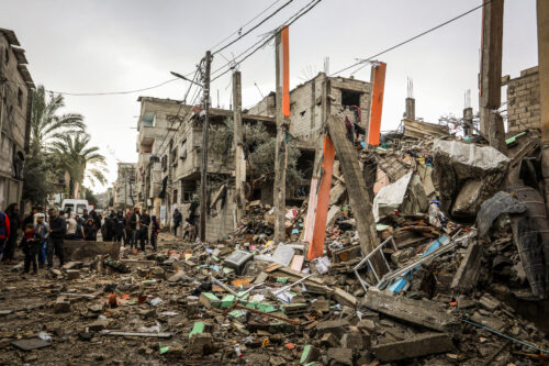 פלסטינים ליד בניין שנהרס בהפגזה אווירית ישראלית ברפיח, ב-27 בינואר 2024 (צילום: עבד רחים ח'טיב / פלאש90)