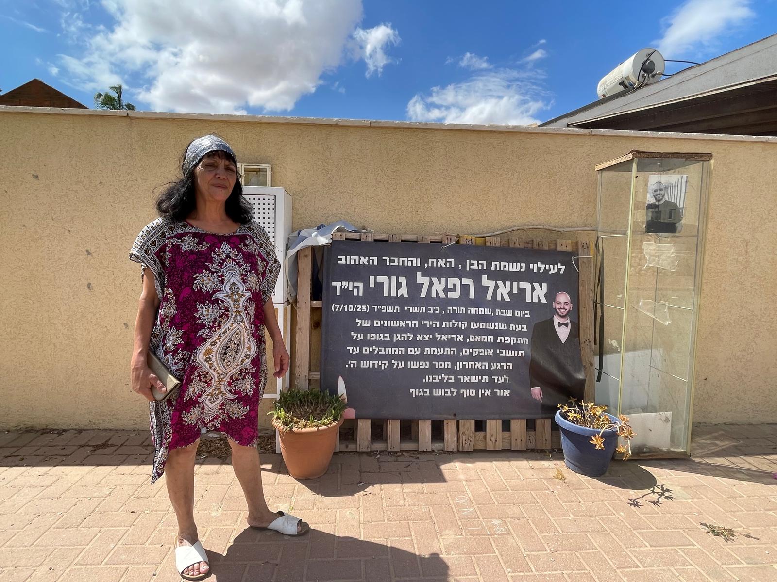 זהבה גורי ליד שלט שמנציח את בנה אריאל רפאל, בשכונת מישור הגפן באופקים (צילום: יאנה פבזנר)