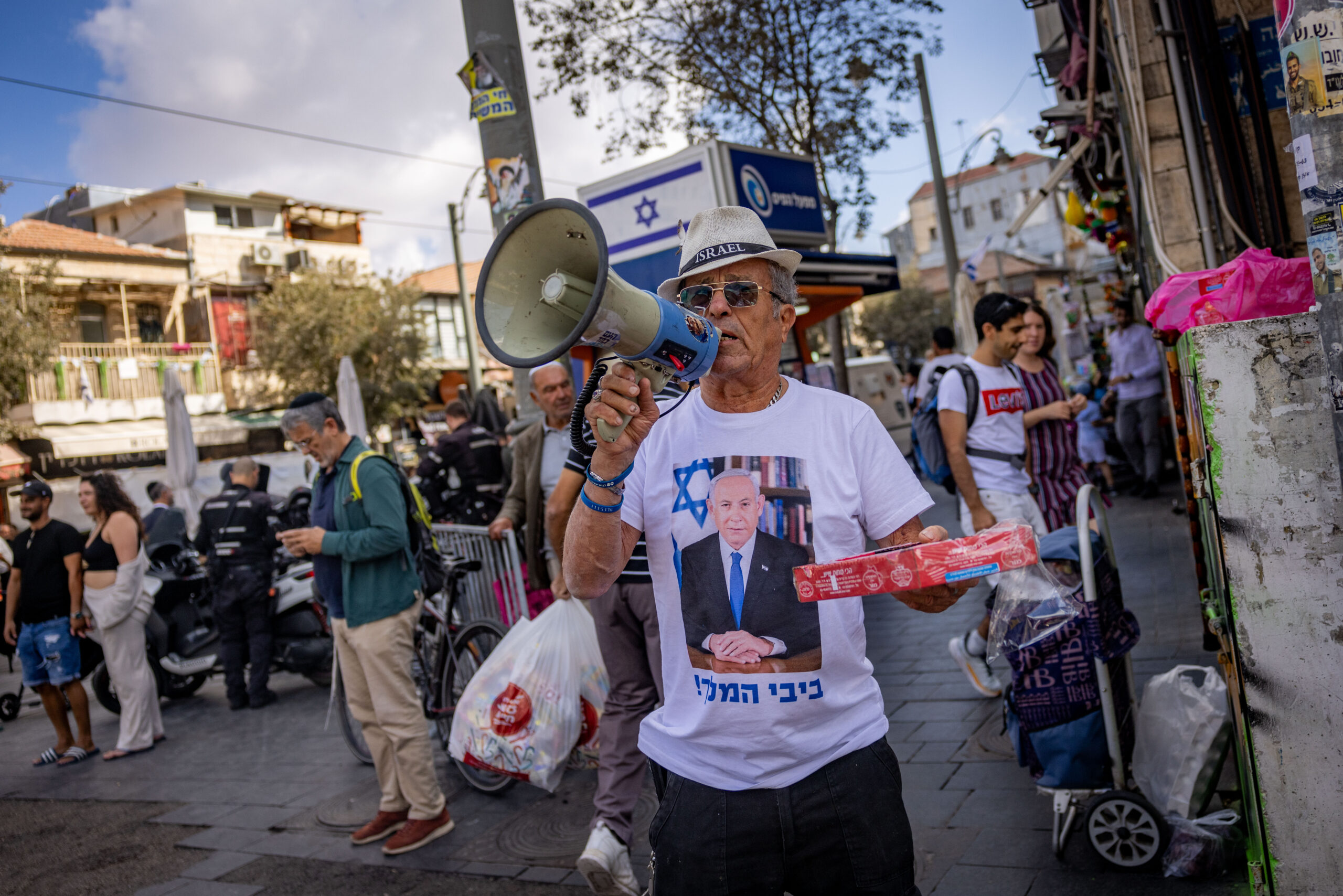 ישראלי מחלק ממתקים בשוק מחנה יהודה בירושלים, אחרי חיסולו של יחיא סינוואר, ב-18 באוקטובר 2024 (צילום: יונתן זינדל / פלאש90)