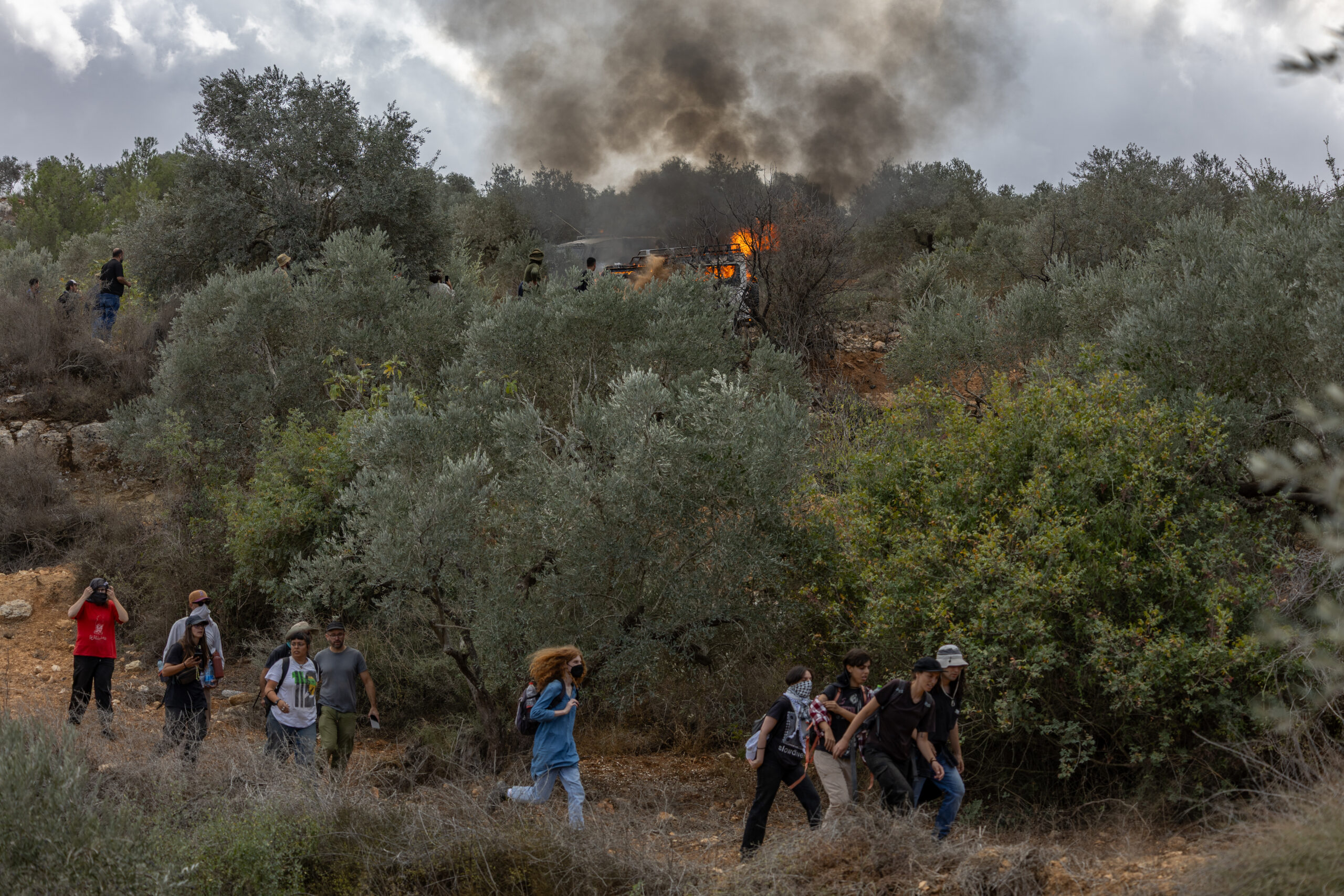 מתנחלים מציתים רכב במהלך מסיק בכפר ביתא, ב-10 באוקטובר 2025 (צילום: אבישי מוהר / אקטיבסטילס)