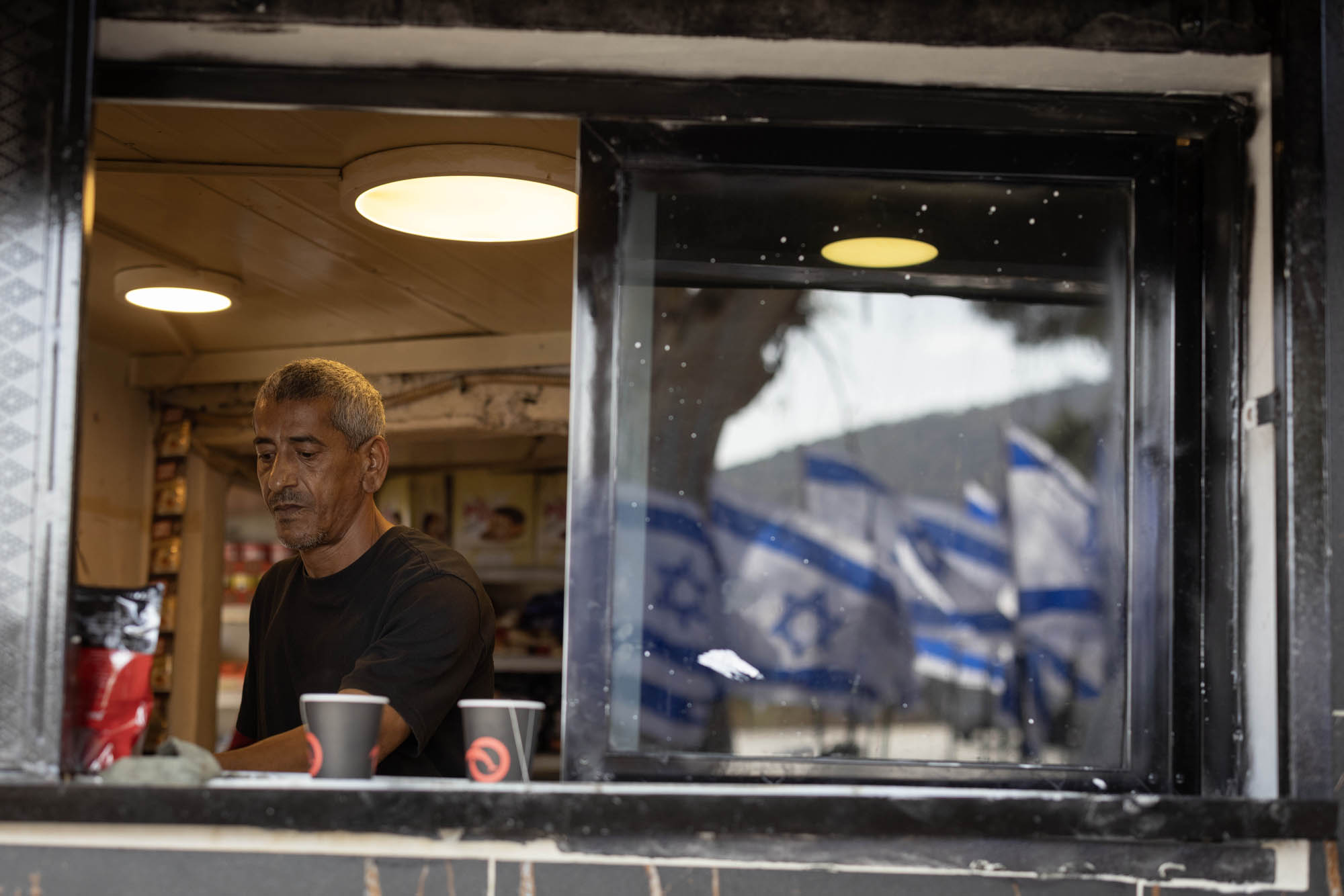 מועין חוסיין בחנות שלו על כביש 60, שמתנחלים הציבו סביבה מאות דגלי ישראל (צילום: אורן זיו) מועין חוסיין בחנות שלו על כביש 60, שמתנחלים הציבו סביבה מאות דגלי ישראל (צילום: אורן זיו)
