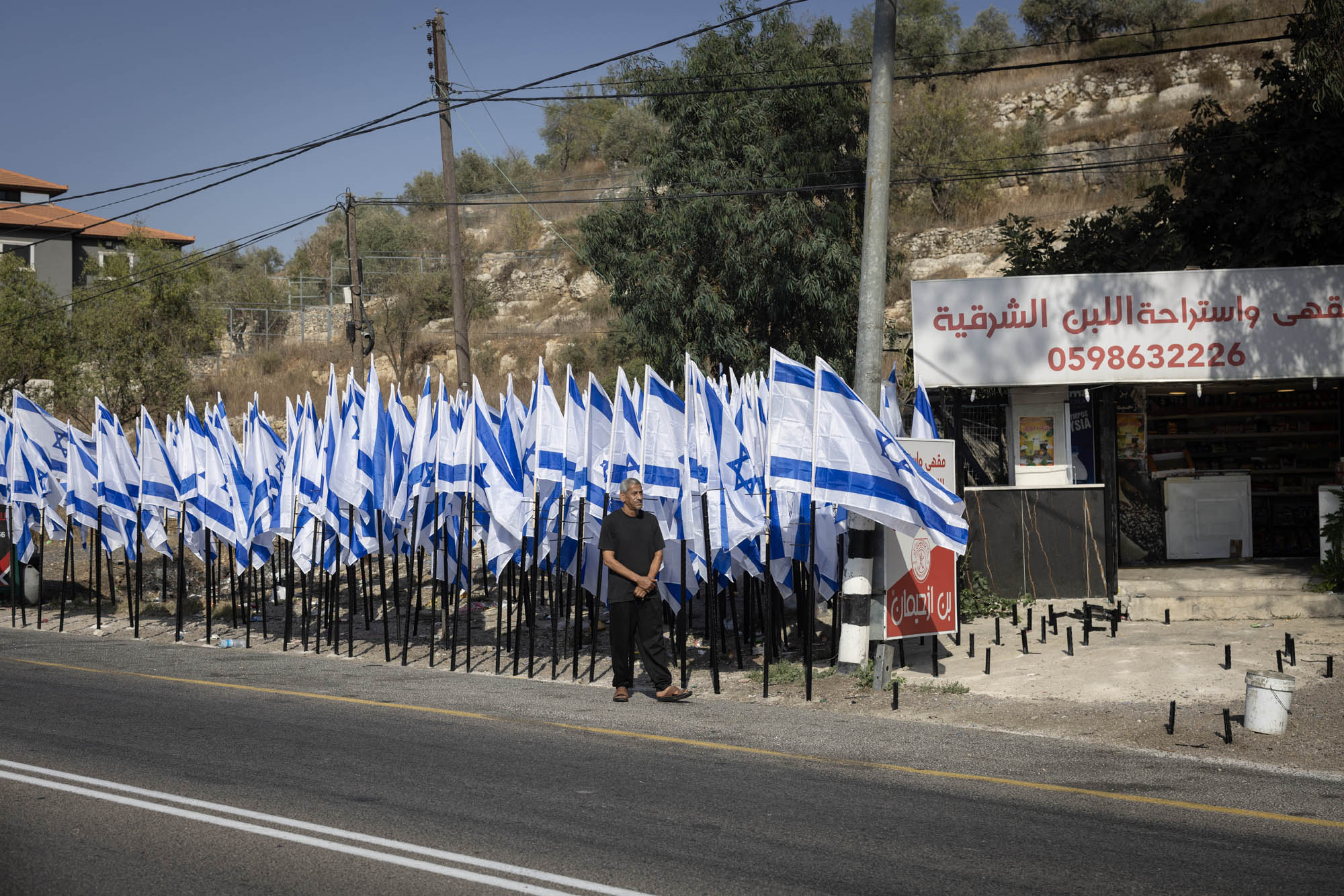 מועין חוסיין בחנות שלו על כביש 60, שמתנחלים הציבו סביבה מאות דגלי ישראל (צילום: אורן זיו)